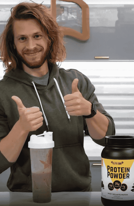 A man giving two thumbs up with a protein shake and a container of EliteCore Protein Powder on the table in front of him.