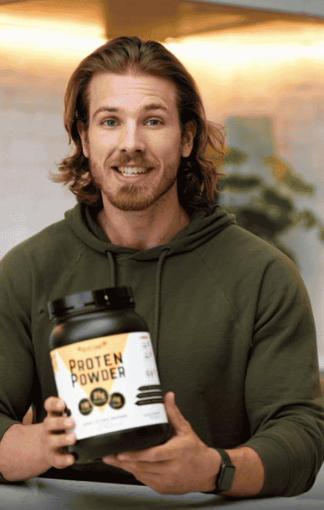 A man holding a container of EliteCore Protein Powder, sharing how it helped him gain more muscle and improve his fitness.