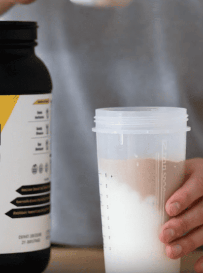 A person making a high protein milkshake with no added sugar using EliteCore Sugar-Free Chocolate Protein Powder.