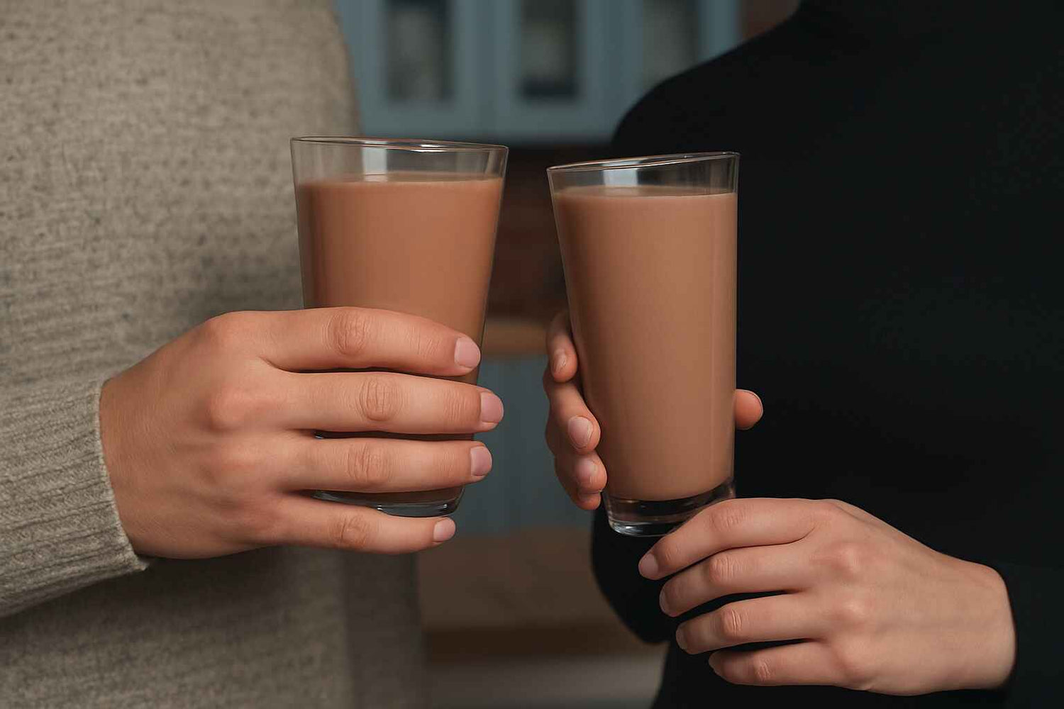 Two people holding glasses of delicious high protein chocolate drinks, which they made using EliteCore chocolate protein powder.